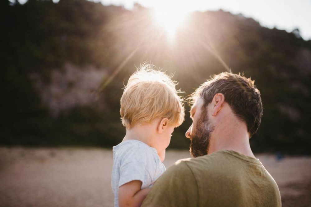 Father holding young child outdoors at sunset representing calm family support and Neurofeedback care for NDIS participants and DVA clients across Australia.