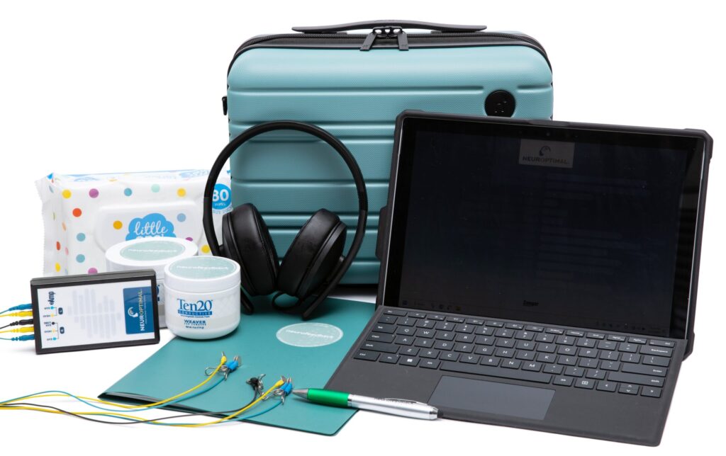 NeurOptimal Neurofeedback Rentals full home training kit including laptop, Z-Amp, sensors, conductive paste, wipes, and headphones neatly arranged with teal carry case.