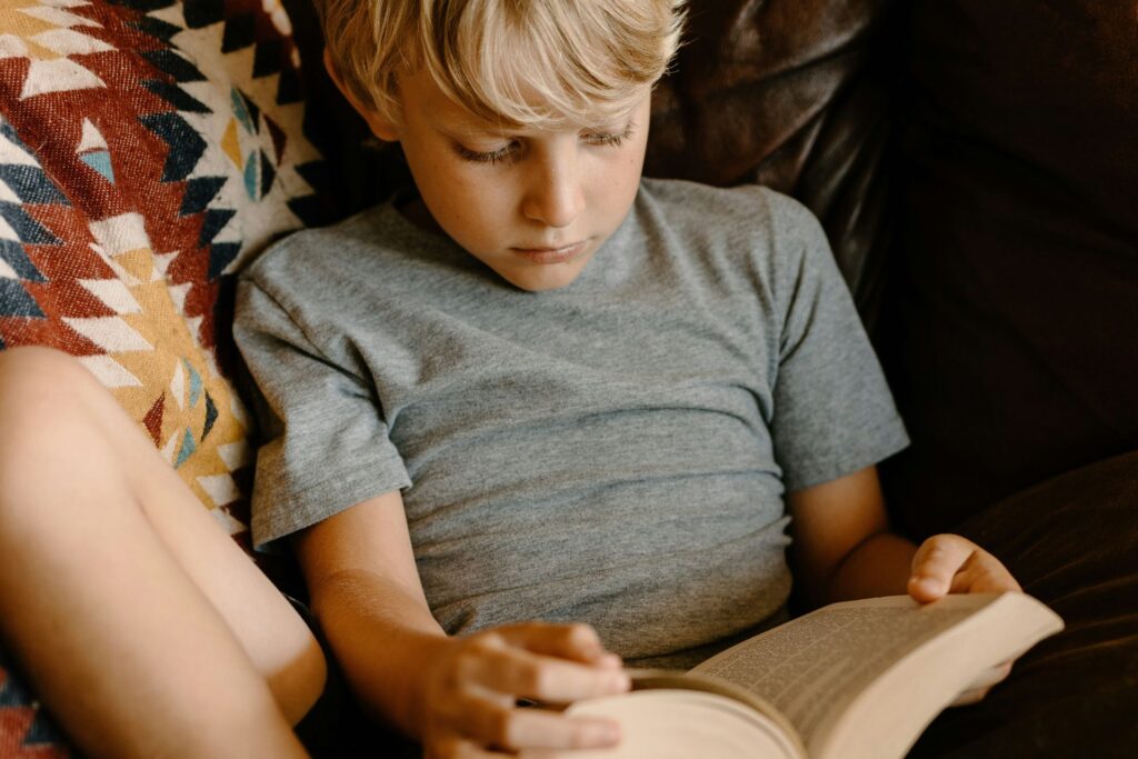 Young boy reading a book calmly representing improved focus and reduced restlessness using NeurOptimal®