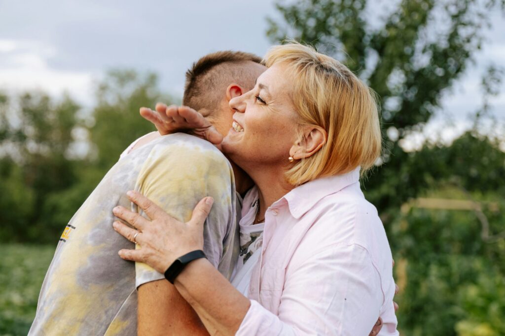 Mother and adult son hugging outdoors, representing improved connection, reduced stress, and better sleep with Neurofeedback
