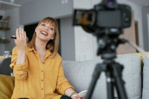 Woman recording content at home while smiling and speaking to a camera, appearing calm and engaged
