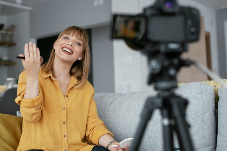 Woman recording content at home while smiling and speaking to a camera, appearing calm and engaged