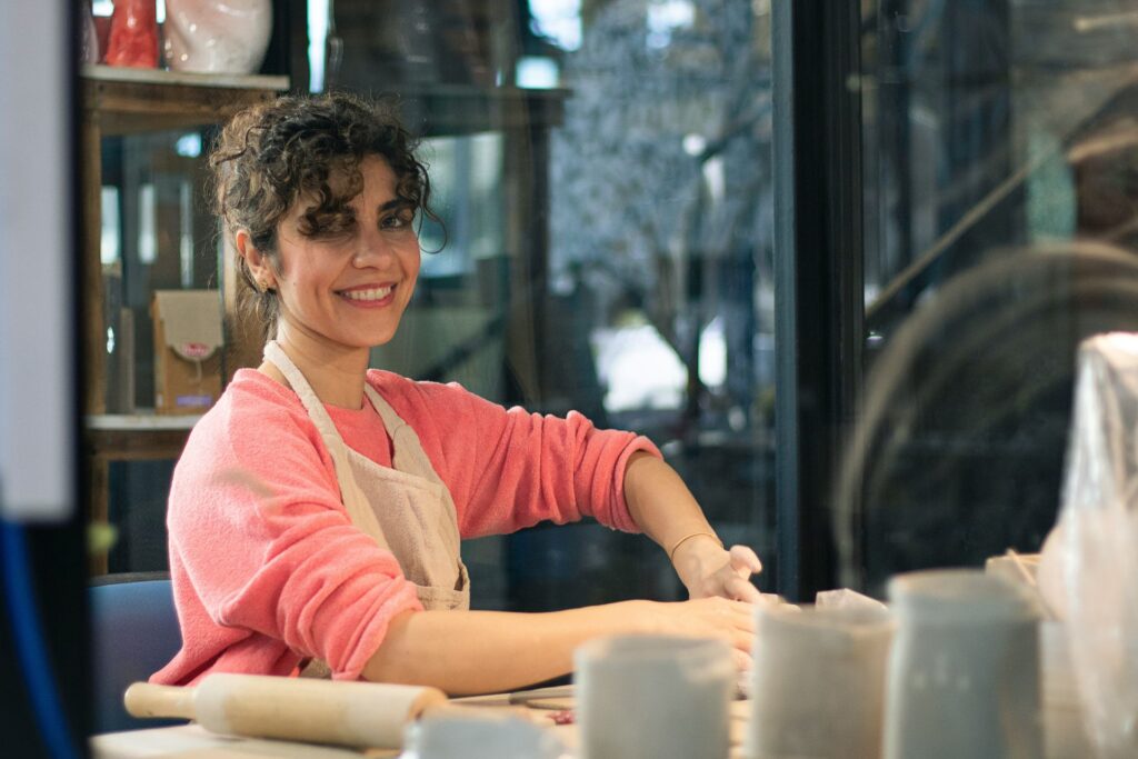 Woman working with her hands at a table in a creative workspace, appearing focused and calm