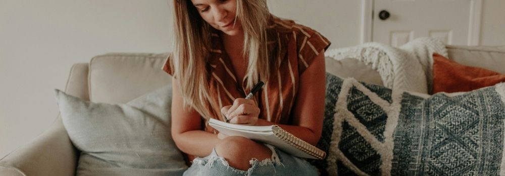 Woman writing in a journal at home, representing reflection and tracking changes during a fertility journey