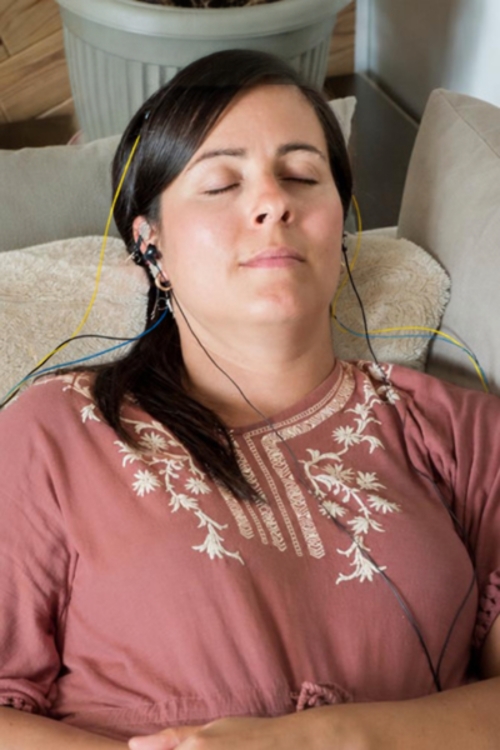 Woman relaxing at home while wearing NeurOptimal neurofeedback sensors during a fertility wellbeing session