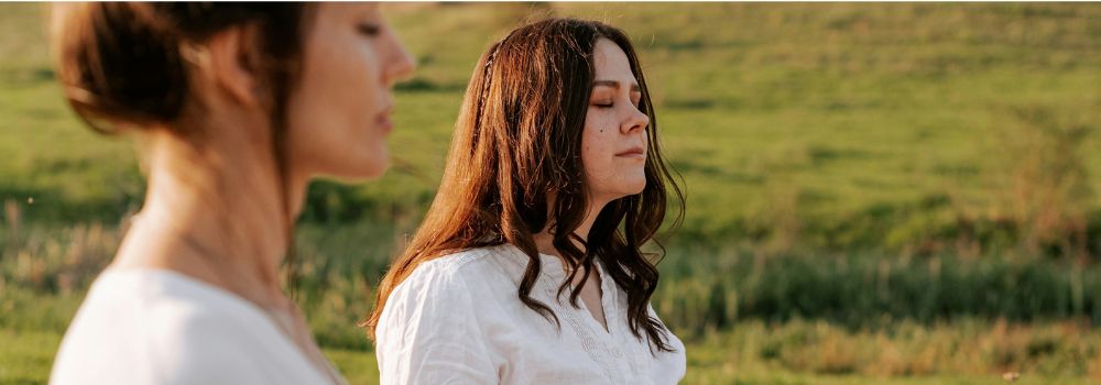 Women meditating outdoors, representing deeper self-awareness, mindfulness and personal growth practices