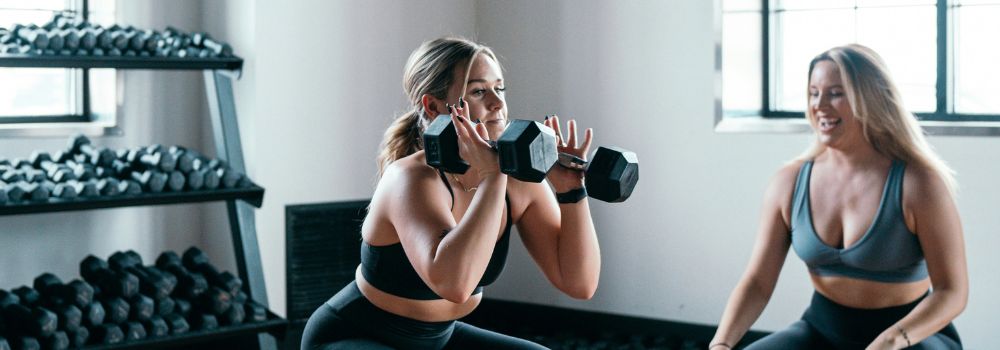 Woman lifting weights during a workout, representing making difficult challenges feel easier through greater resilience