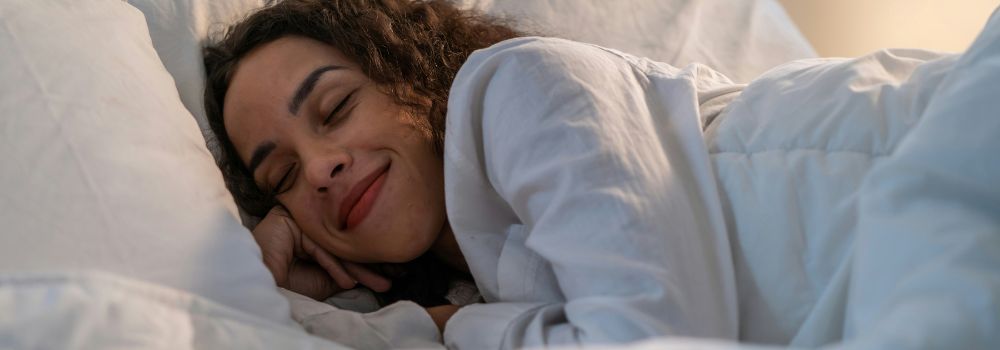 Woman sleeping peacefully in bed, representing restorative sleep and catching up on sleep debt