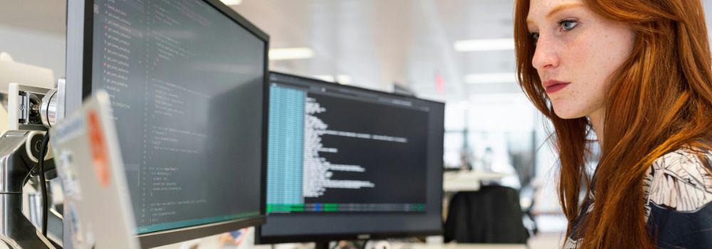 Woman concentrating on computer screens, representing improved focus after better rest