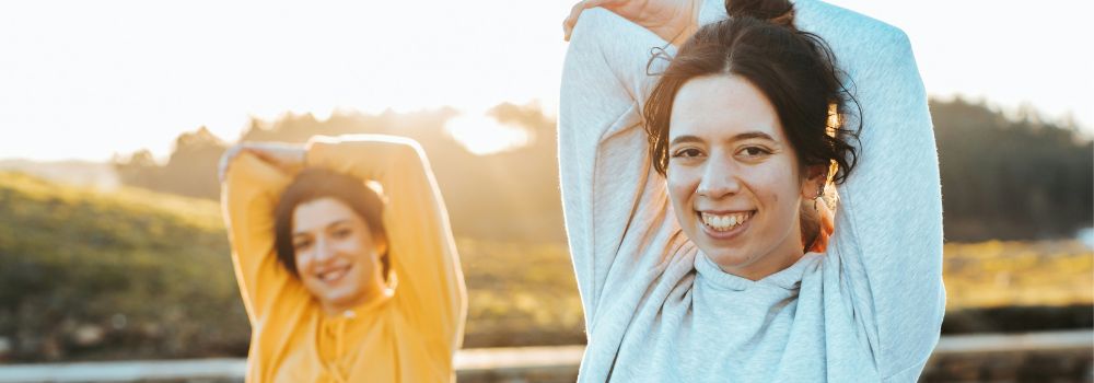 Women stretching outdoors, representing more energy after better sleep