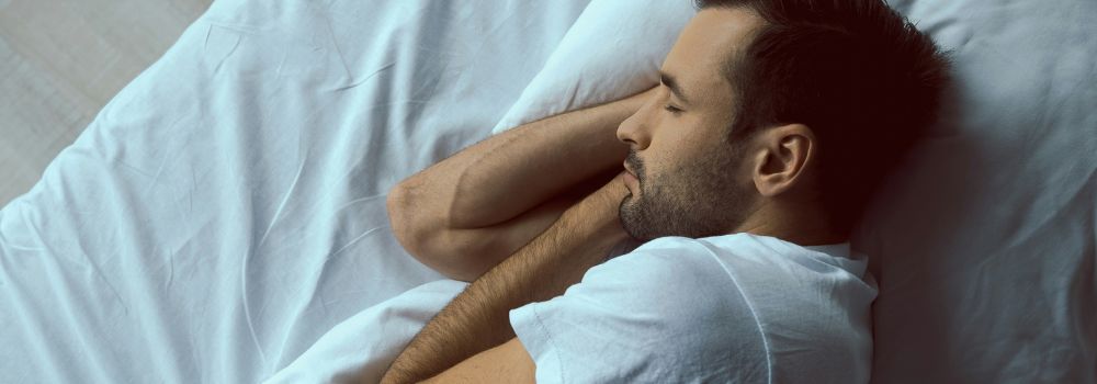 Man sleeping peacefully in bed, representing staying asleep throughout the night