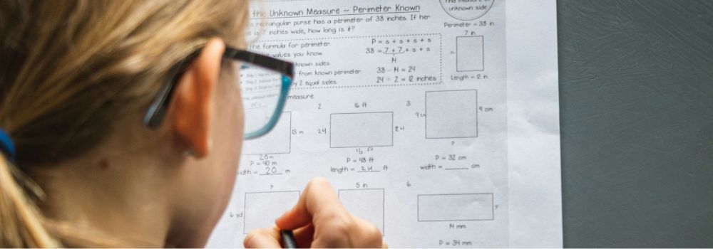 Student completing a maths worksheet while studying for an exam