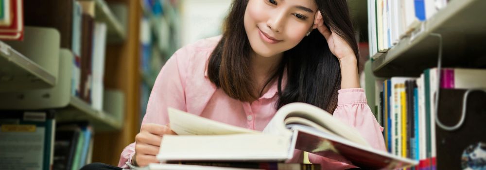 Student enjoying reading and studying in a library