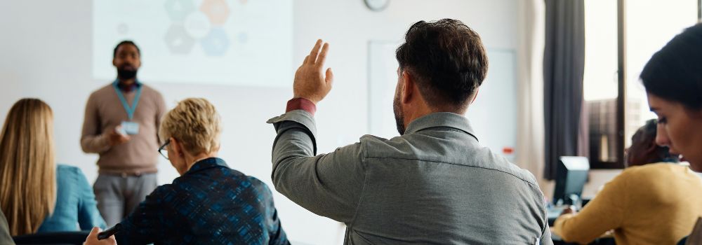 Student raising his hand during a class while engaging with new information