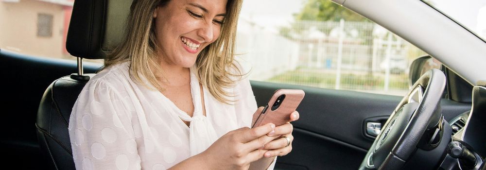 Woman smiling while looking at her phone, representing reconnecting with happiness and enjoyment after trauma
