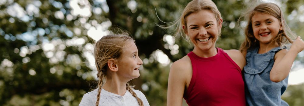 Mother enjoying time outdoors with her children, representing breaking cycles and creating a positive family environment after trauma