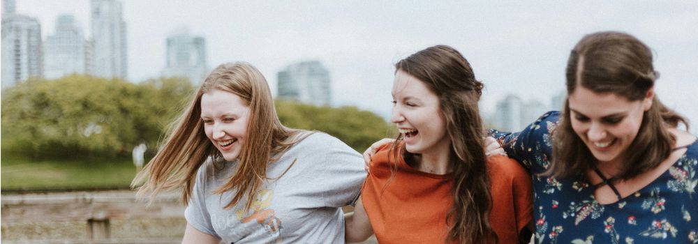 Friends laughing together outdoors, representing nervous system regulation, connection and emotional wellbeing after trauma