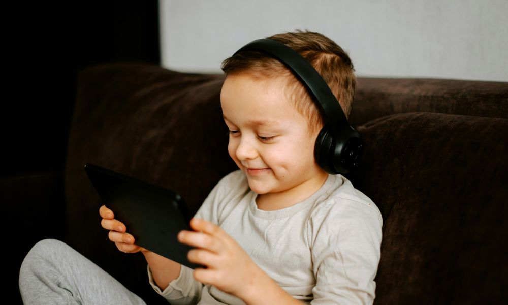 Young child wearing headphones and using a tablet at home, illustrating a comfortable environment for NeurOptimal neurofeedback sessions