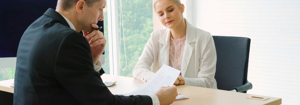 Two business professionals reviewing documents in a meeting, representing self-control, thoughtful decisions and workplace performance