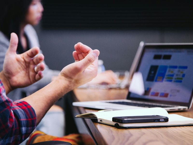 Business professional gesturing during a meeting with colleagues, representing communication, collaboration and workplace performance.