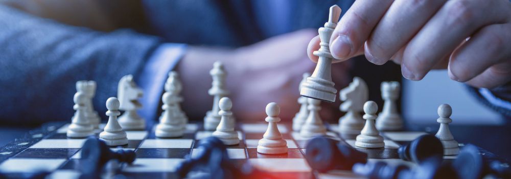 Person moving a chess piece during a game, representing strategic thinking, planning and business decision-making