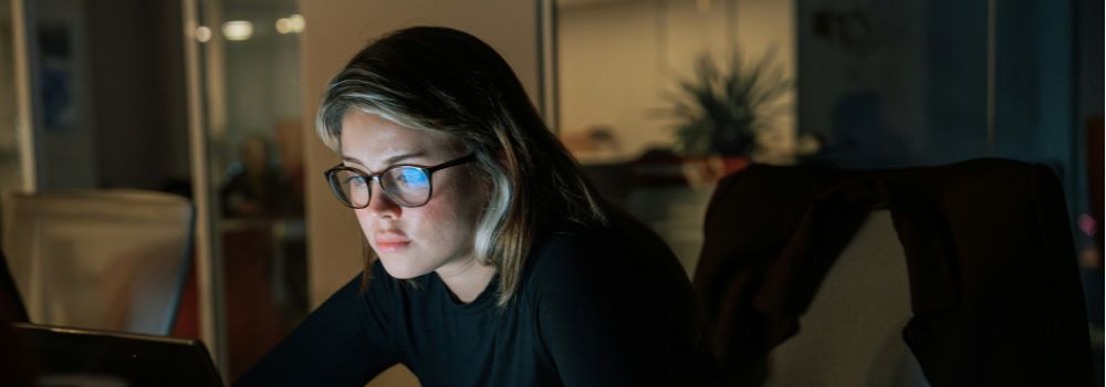 Woman working late on her laptop, representing resilience, focus and managing workplace pressures