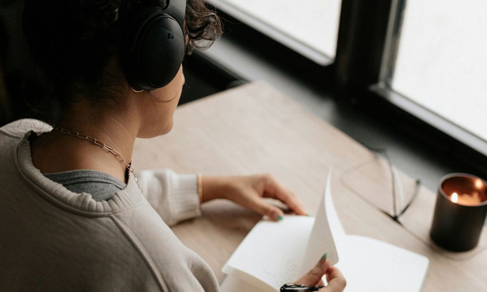 Woman wearing headphones and writing in a notebook, representing tracking personal changes and progress with neurofeedback